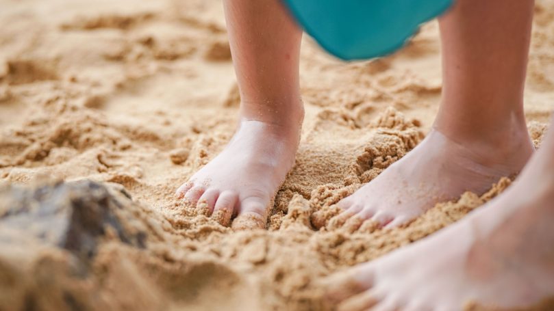 Family Memory Makers Two pairs of bare feet on sandy beach.